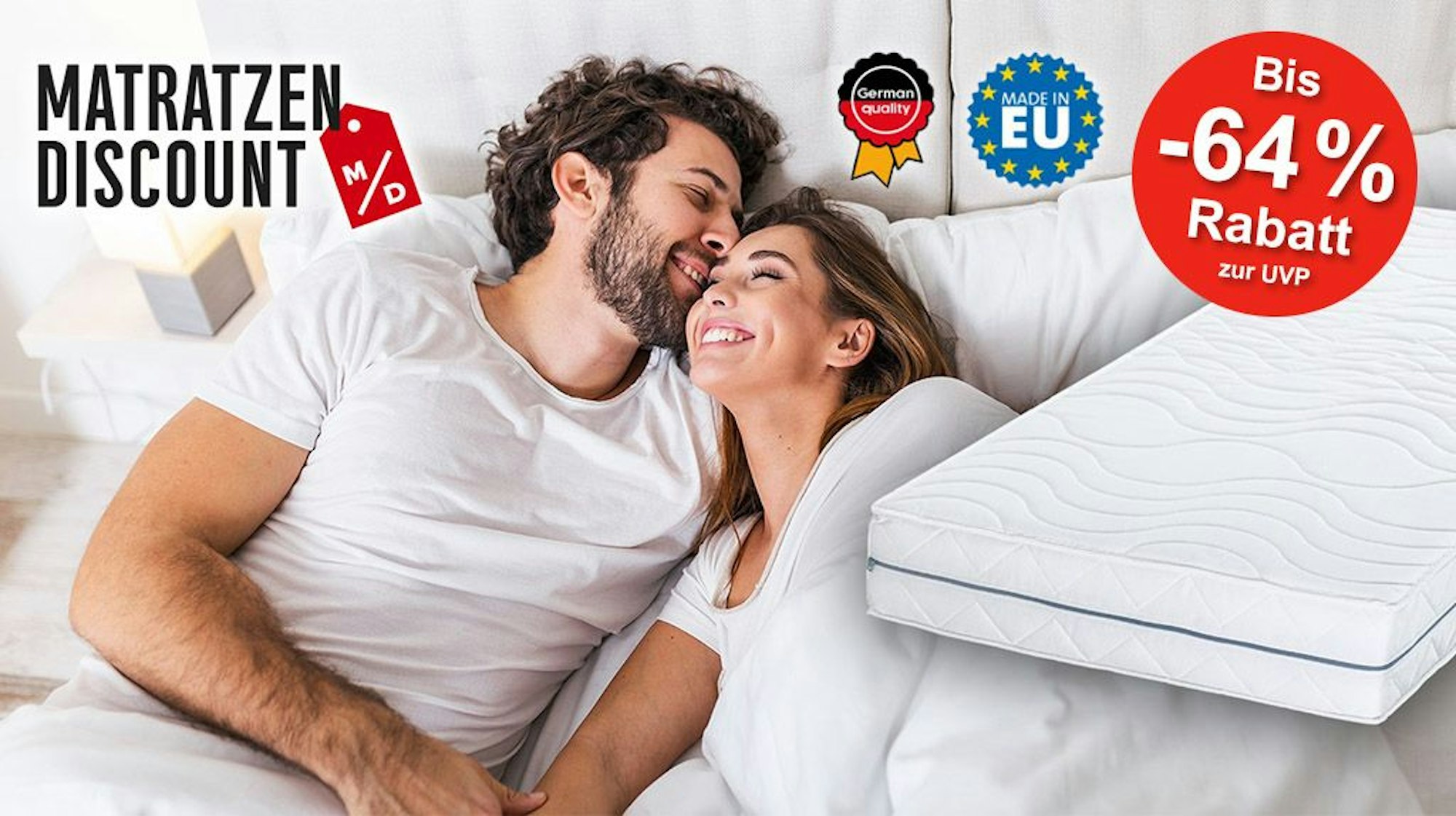 Eine Frau und ein Mann liegen gut gelaunt und fröhlich in einem bequemen Bett.