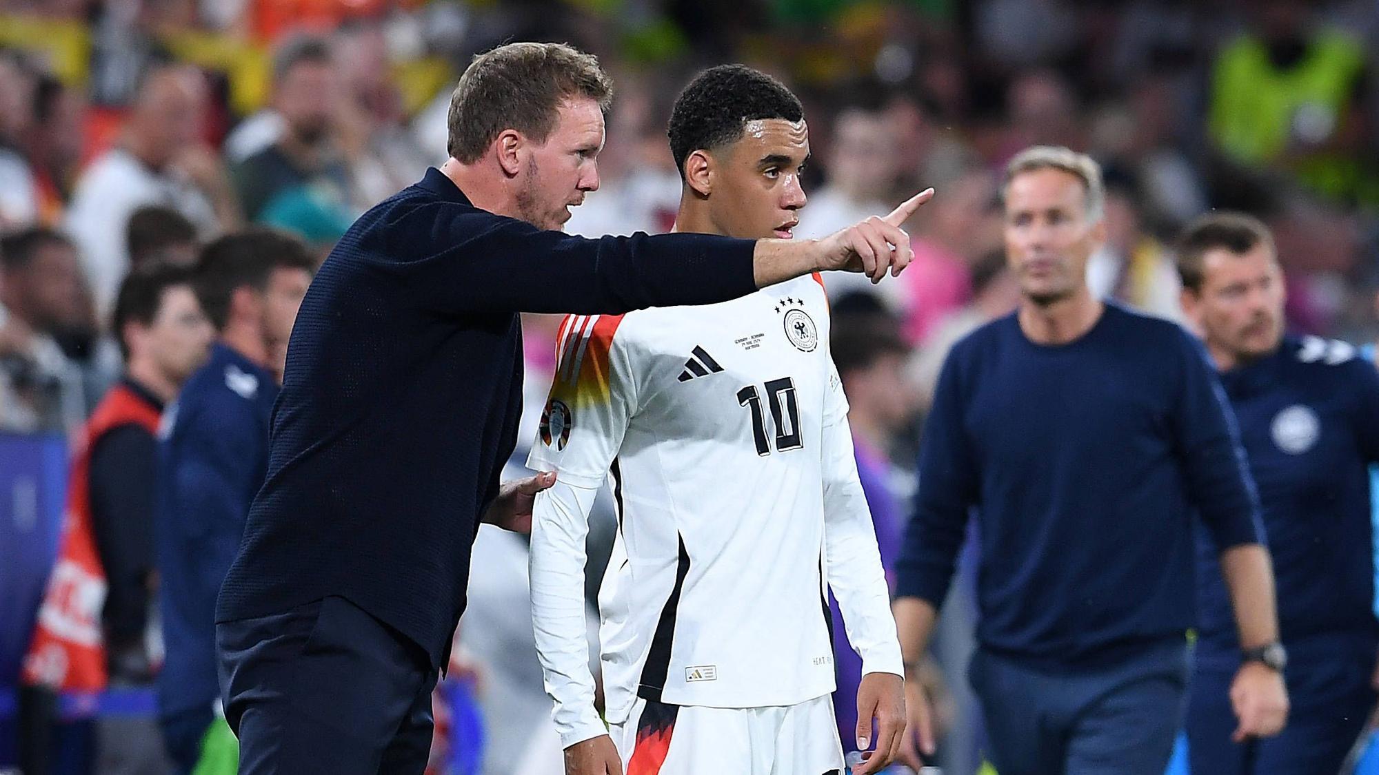Bundestrainer Julian Nagelsmann gibt Jamal Musiala am Spielfeldrand Anweisungen.