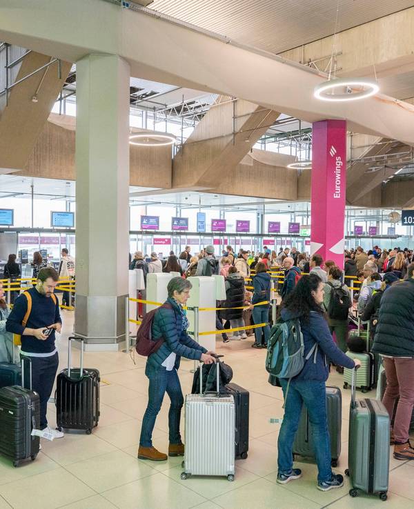 Am Flughafen checken viele Reisende zu ihrem Flug in den Urlaub ein.