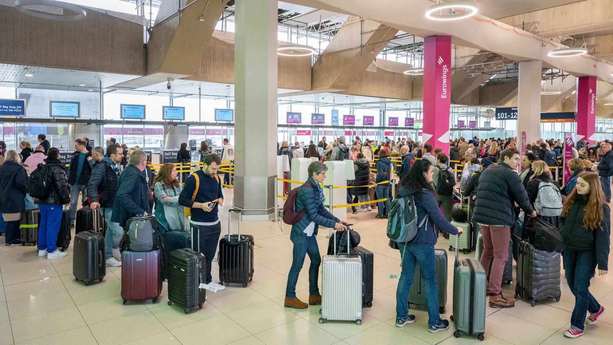 Am Flughafen checken viele Reisende zu ihrem Flug in den Urlaub ein.
