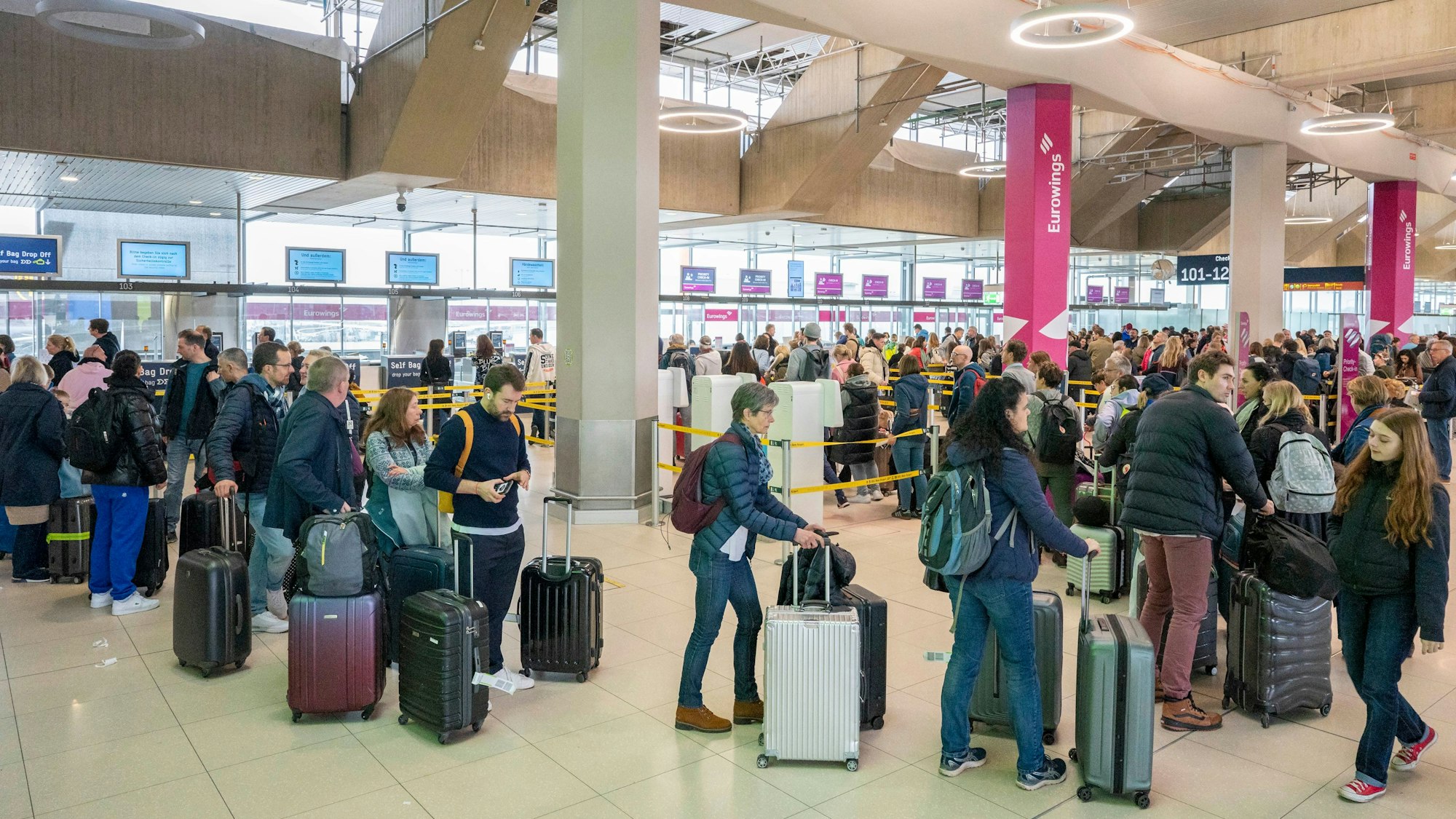 Am Flughafen checken viele Reisende zu ihrem Flug in den Urlaub ein.