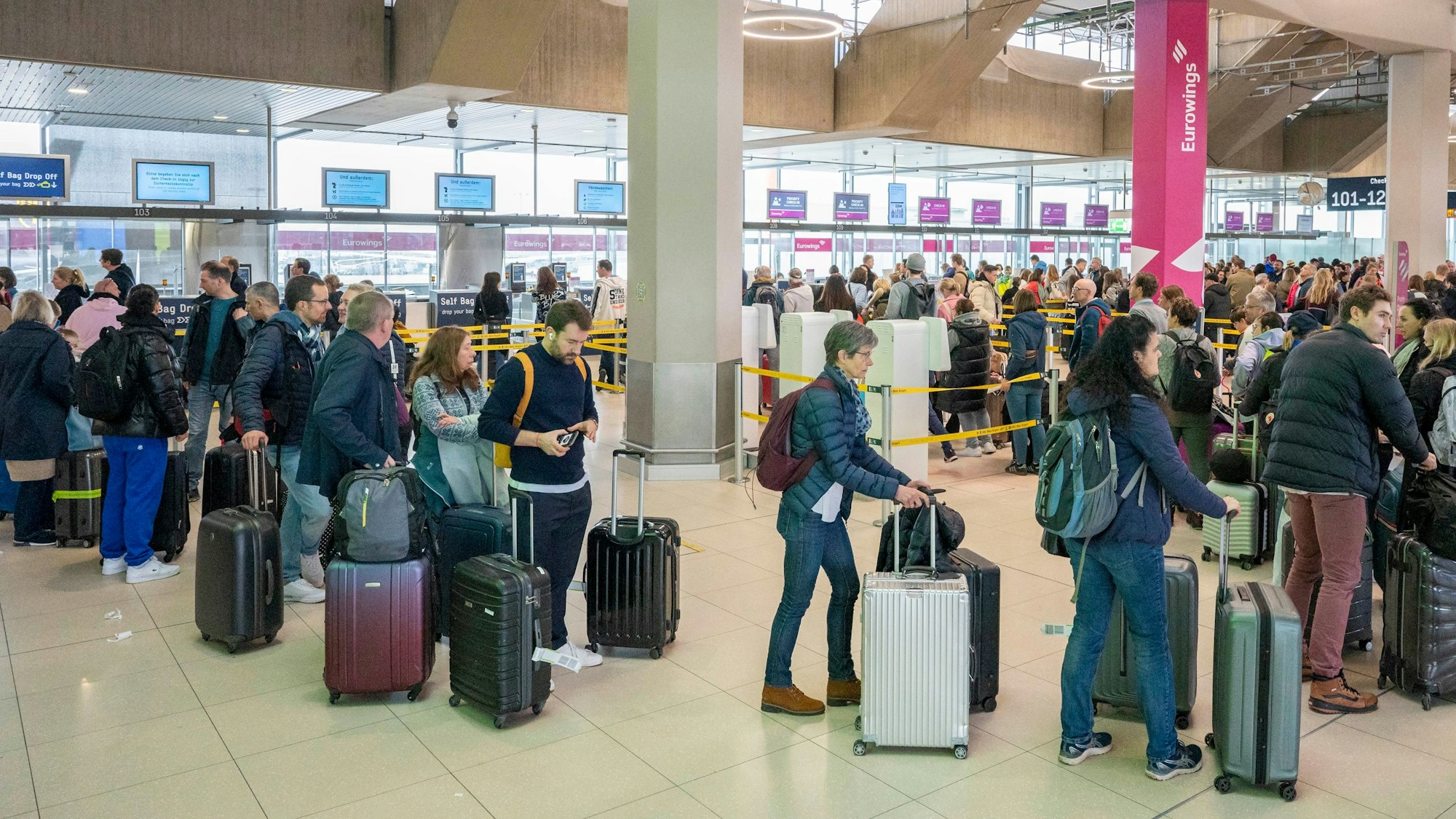 Am Flughafen checken viele Reisende zu ihrem Flug in den Urlaub ein.