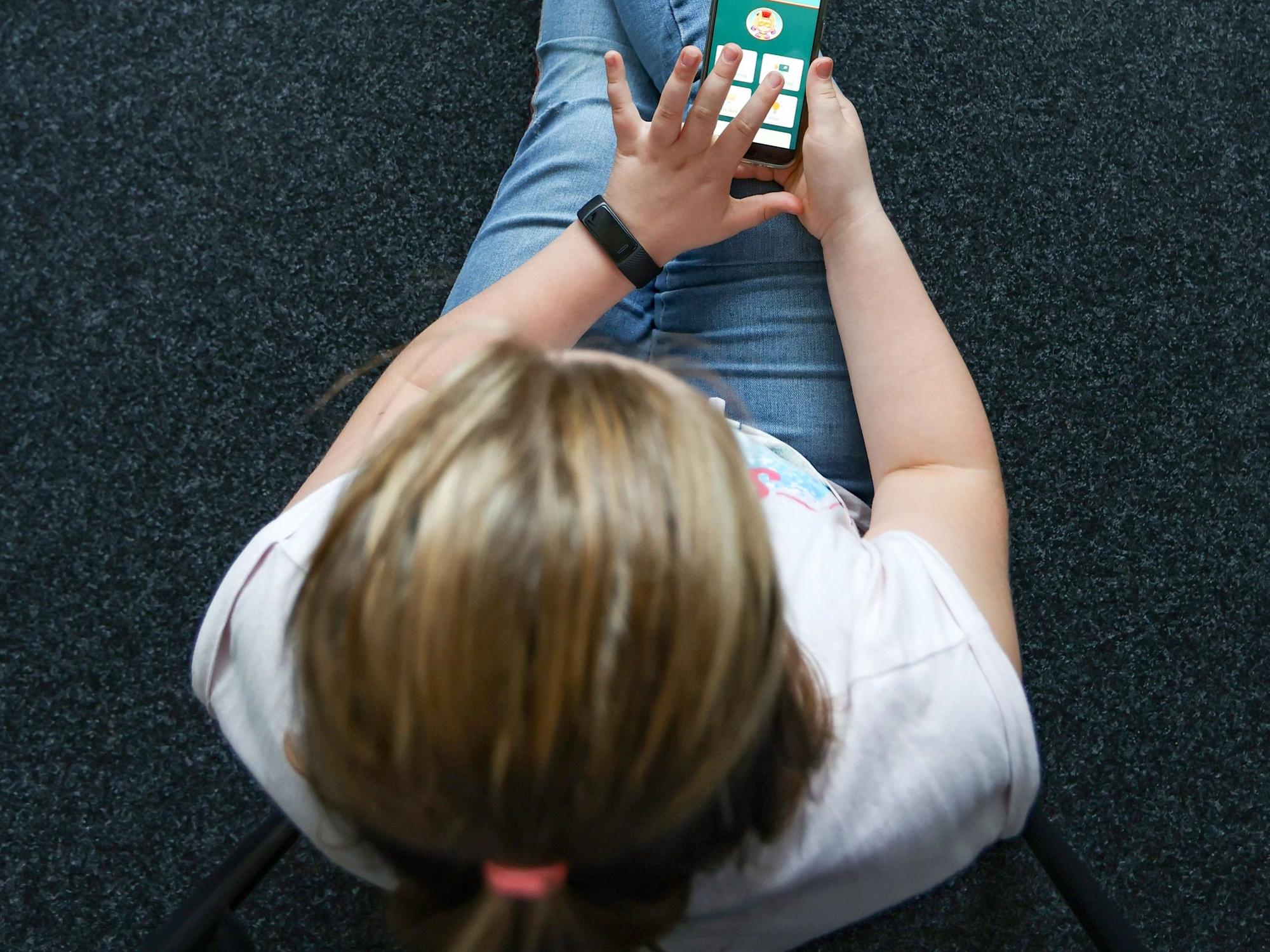 Ein Mädchen spielt an einem Handy.