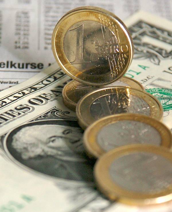 Ein-Euro-Münzen liegen über einer Dollarnote verteilt über den Wechselkursen für Devisen in der Tageszeitung (Symbolbild vom 5. Januar .2004).