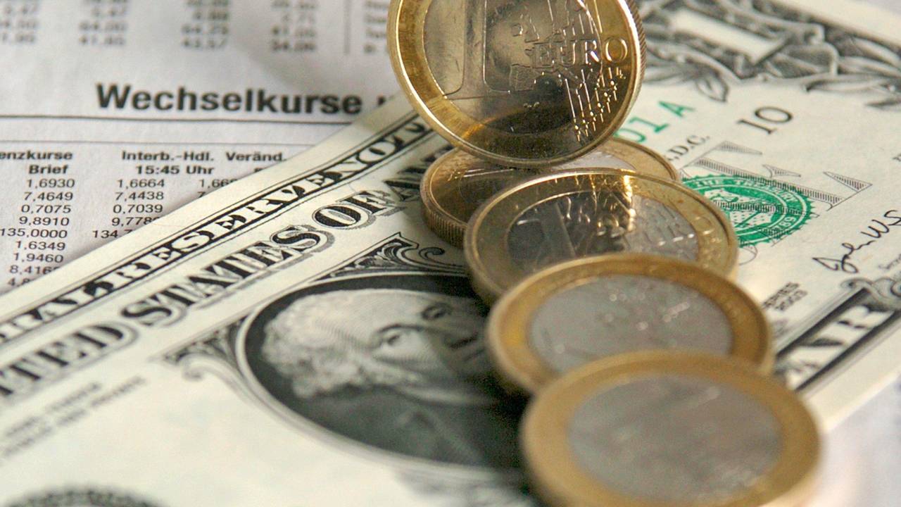Ein-Euro-Münzen liegen über einer Dollarnote verteilt über den Wechselkursen für Devisen in der Tageszeitung (Symbolbild vom 5. Januar .2004).