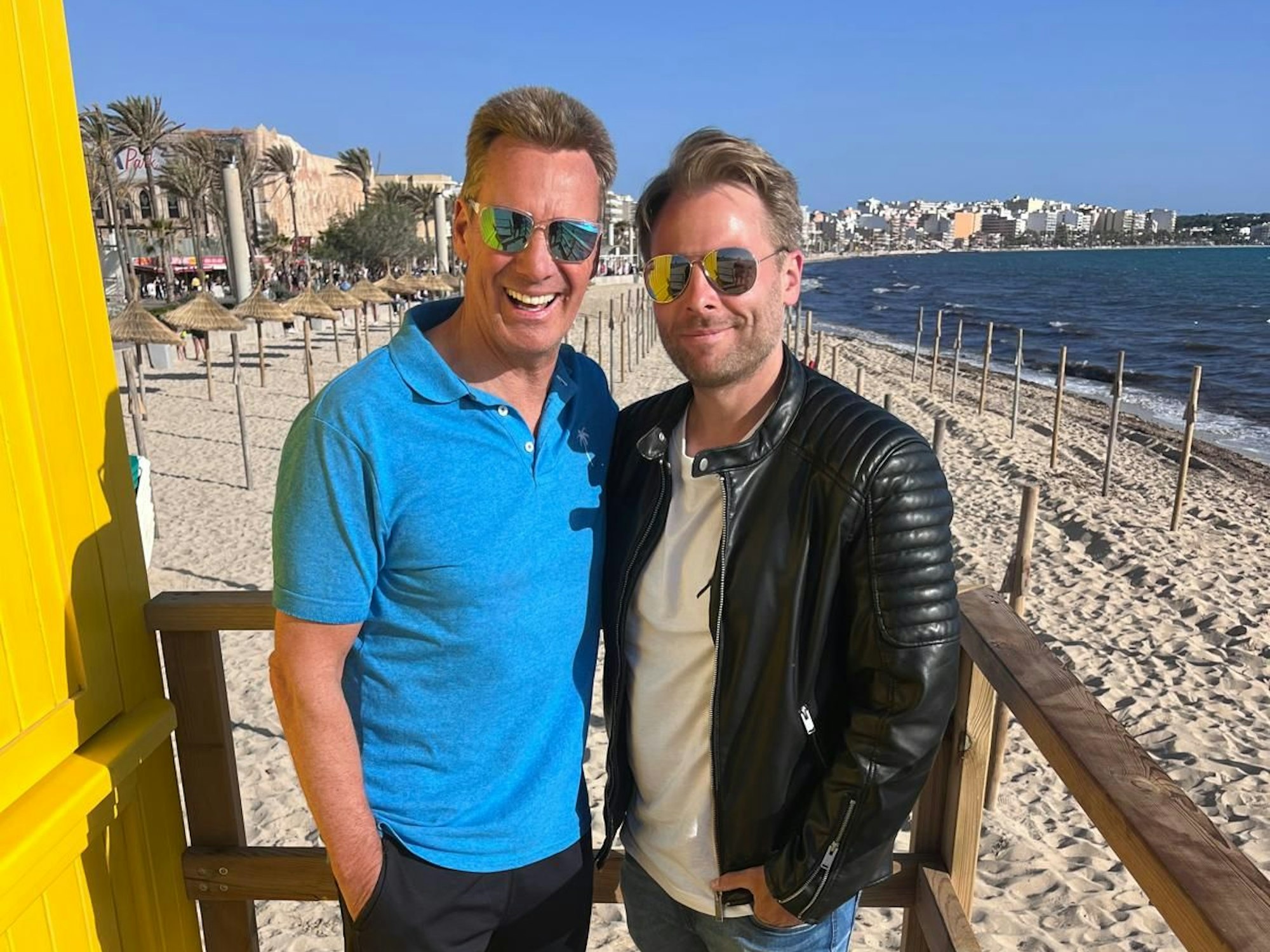 Jürgen Milski und DJ Aaron stehen auf einem Hochsitz an einem Strand auf Mallorca.