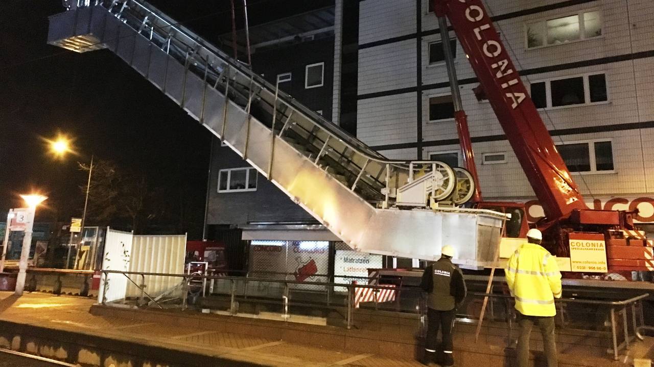 Ein Kran hat eine Rolltreppe am Haken.