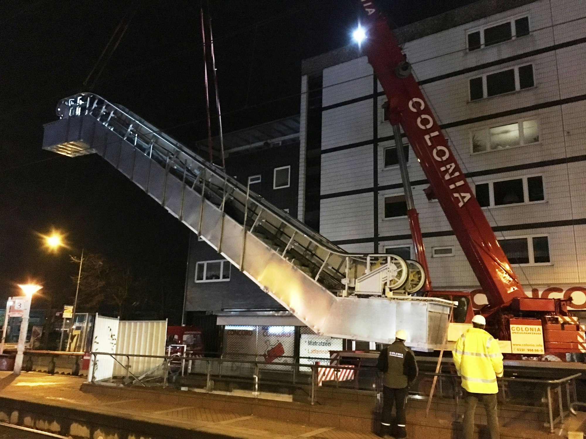 Ein Kran hat eine Rolltreppe am Haken.