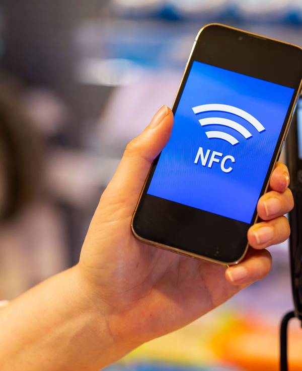 Eine Kundin bezahlt mit Smartphone und NFC mittels hinterlegter EC-Karte im Geschäft.