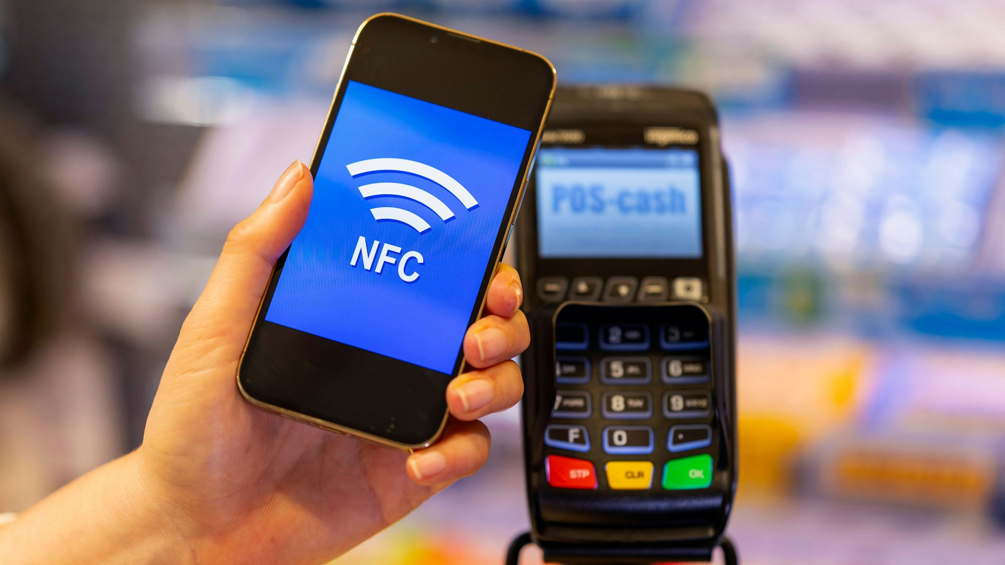 Eine Kundin bezahlt mit Smartphone und NFC mittels hinterlegter EC-Karte im Geschäft.