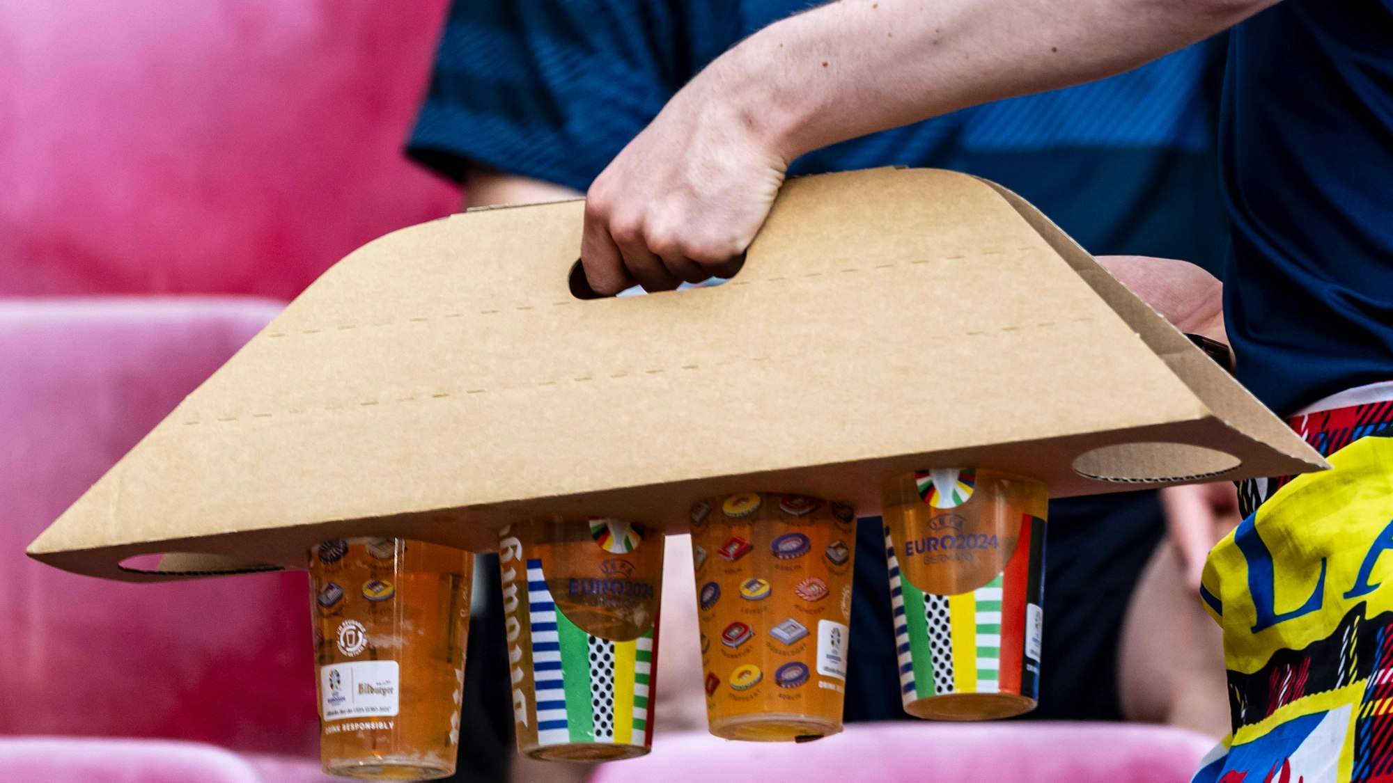 Ein Schottland-Fan bringt vier Becher Bier mit dem praktischen Träger unfallfrei an seinen Platz im Stadion in Köln.