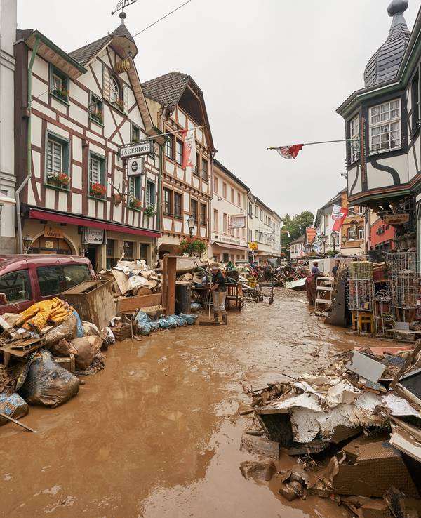 Eine Straße steht voller Wasser, vor den Häusern stapeln sich kaputte Möbel.