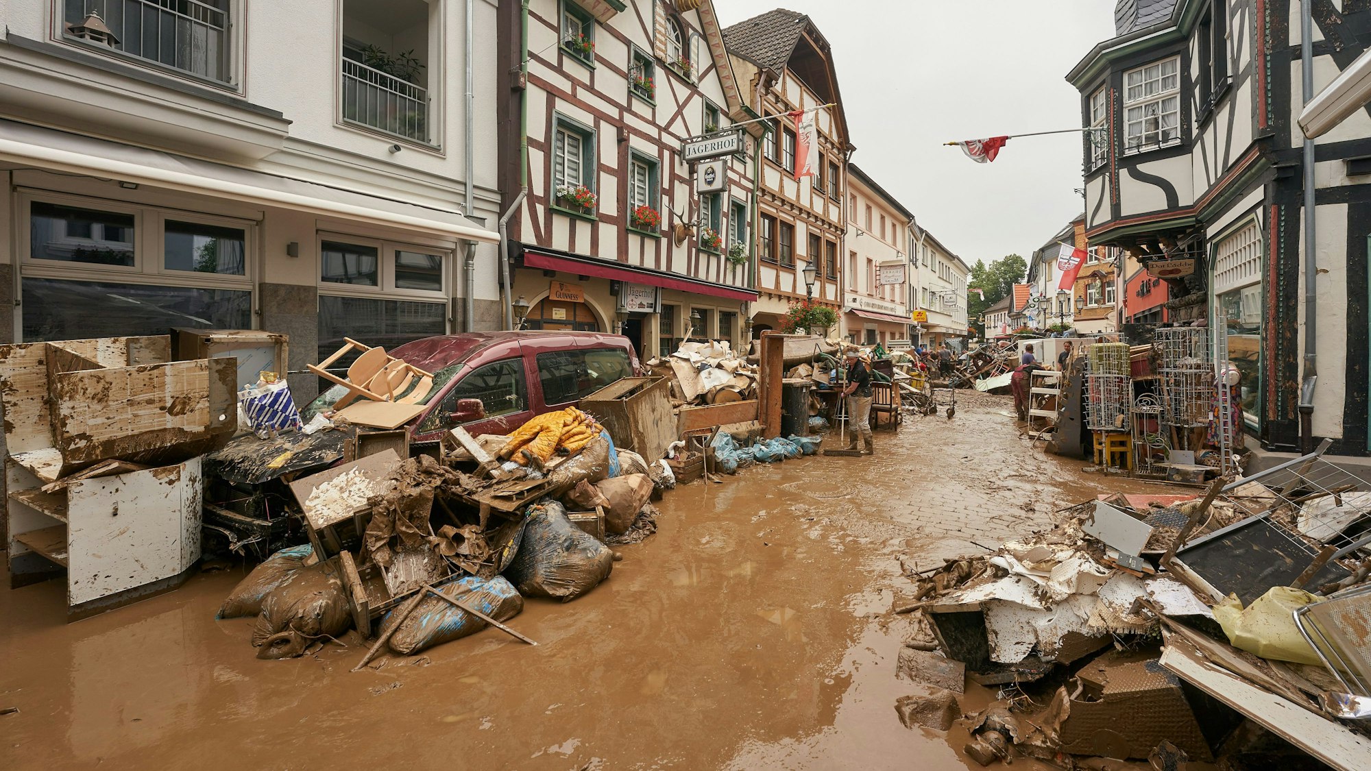 Anwohner und Ladeninhaber versuchen, ihre Häuser vom Schlamm zu befreien und unbrauchbares Mobiliar nach draußen zu bringen.