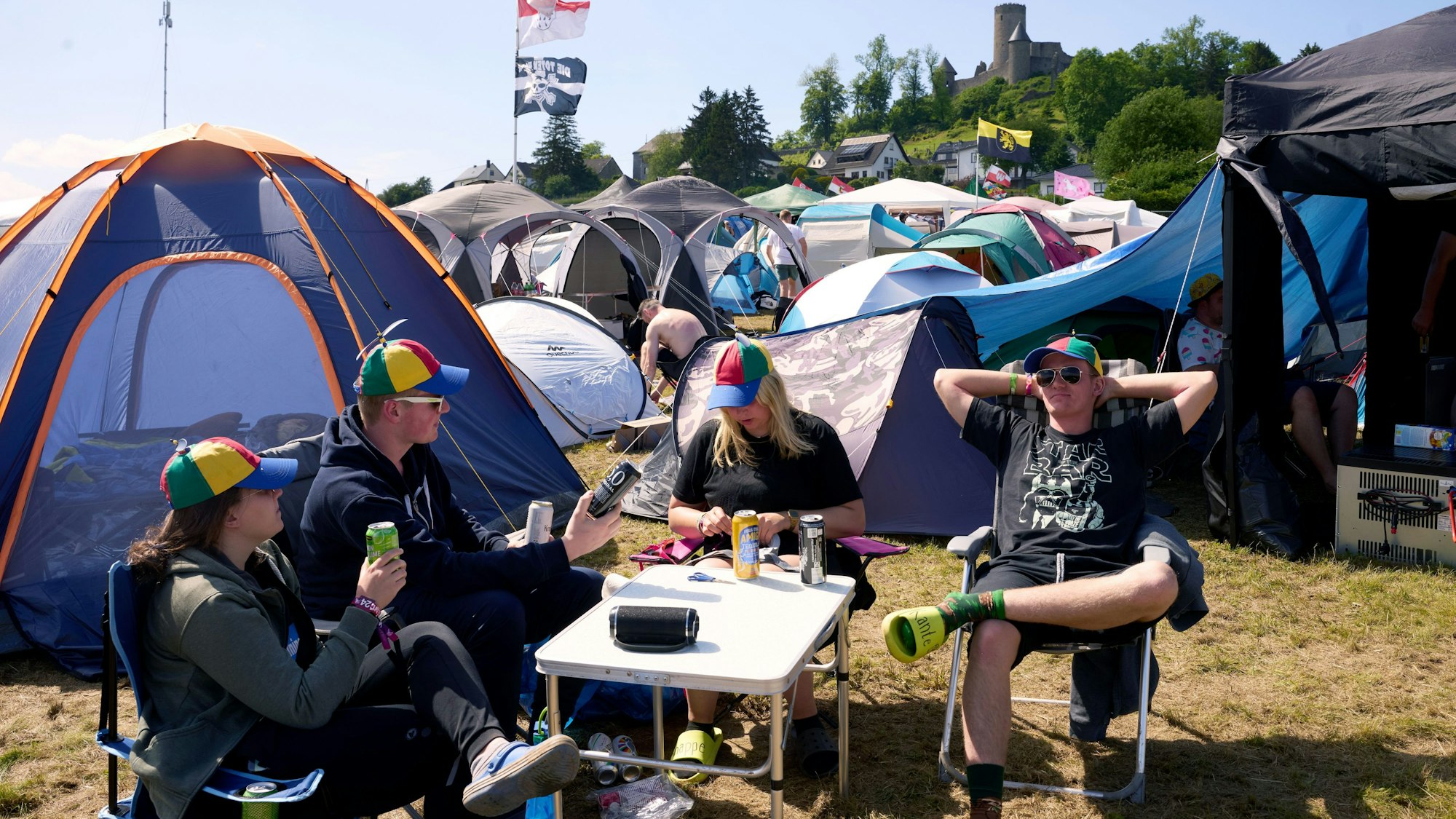 Rockfans sonnen sich am Nürburgring auf dem Campinggelände unterhalb der Nürburg.