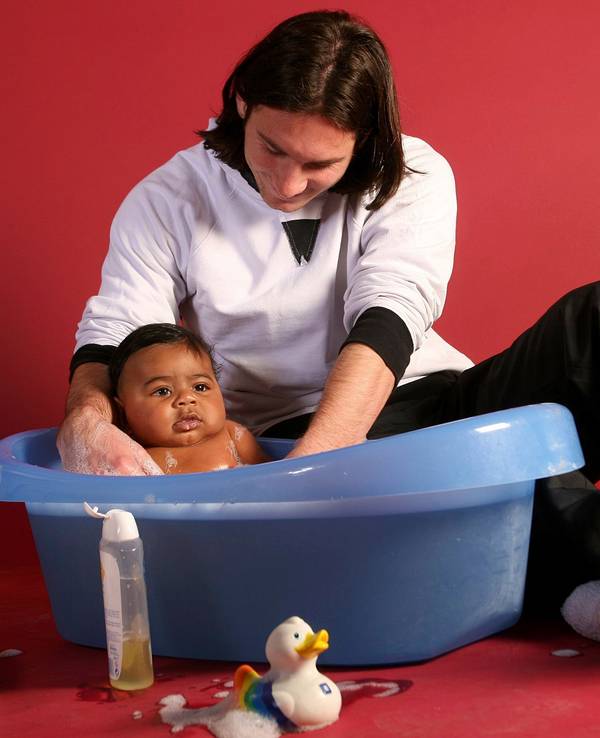 Lionel Messi badet ein Baby in einer Plastikwanne.