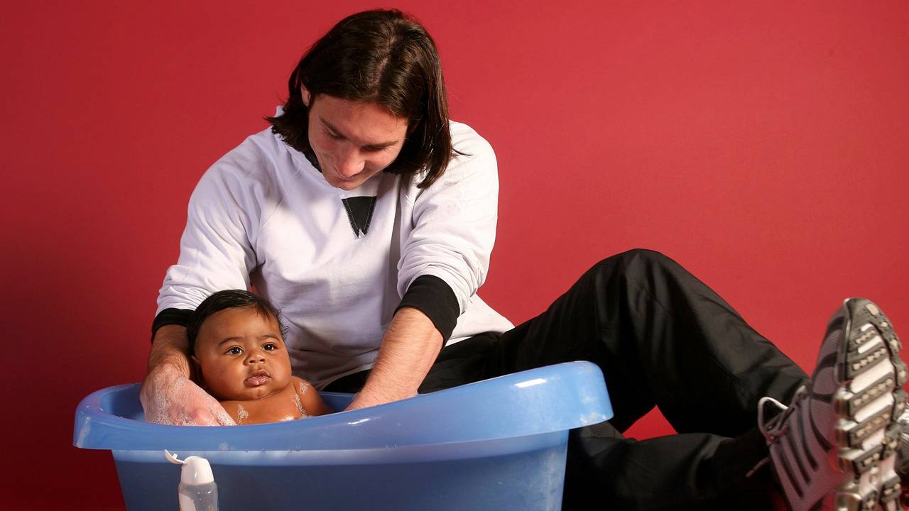 Lionel Messi badet ein Baby in einer Plastikwanne.