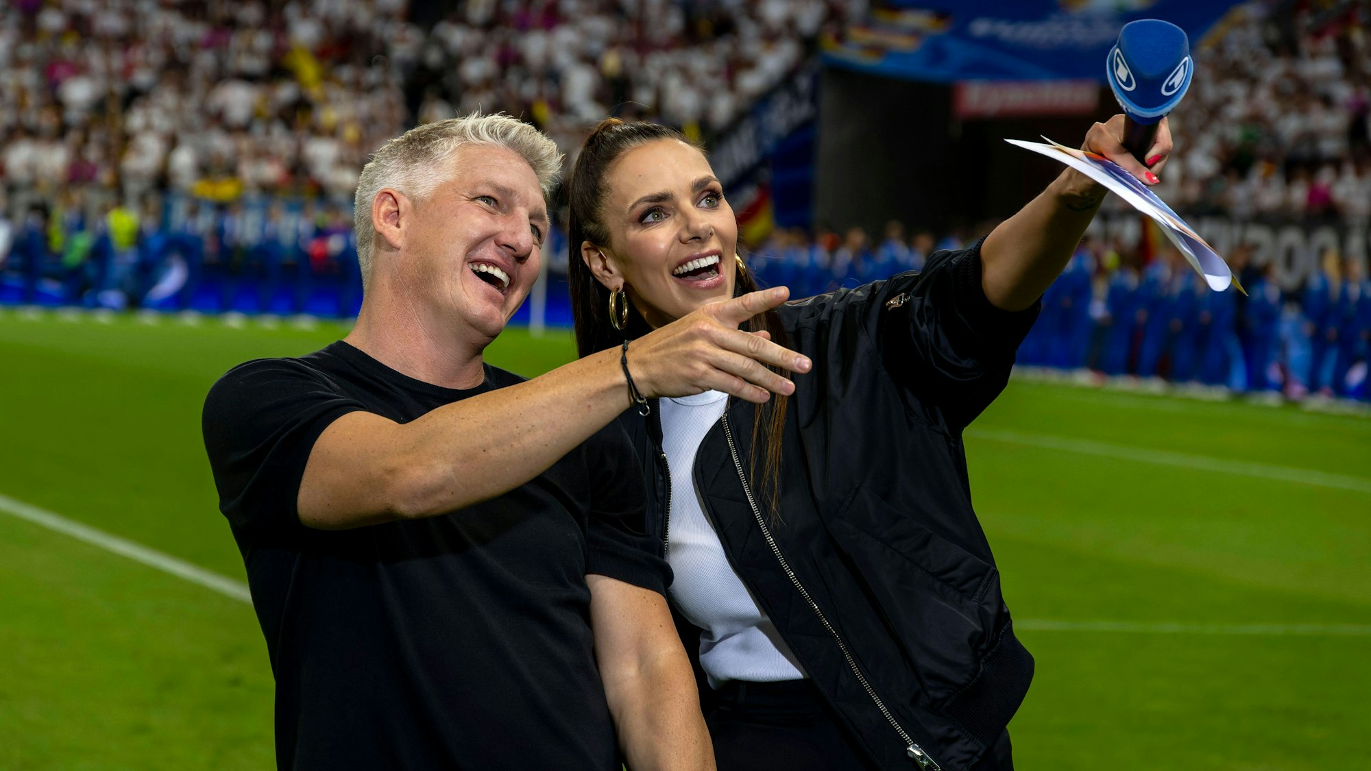 Bastian Schweinsteiger und Esther Sedlaczek lachen über etwas im Publikum.