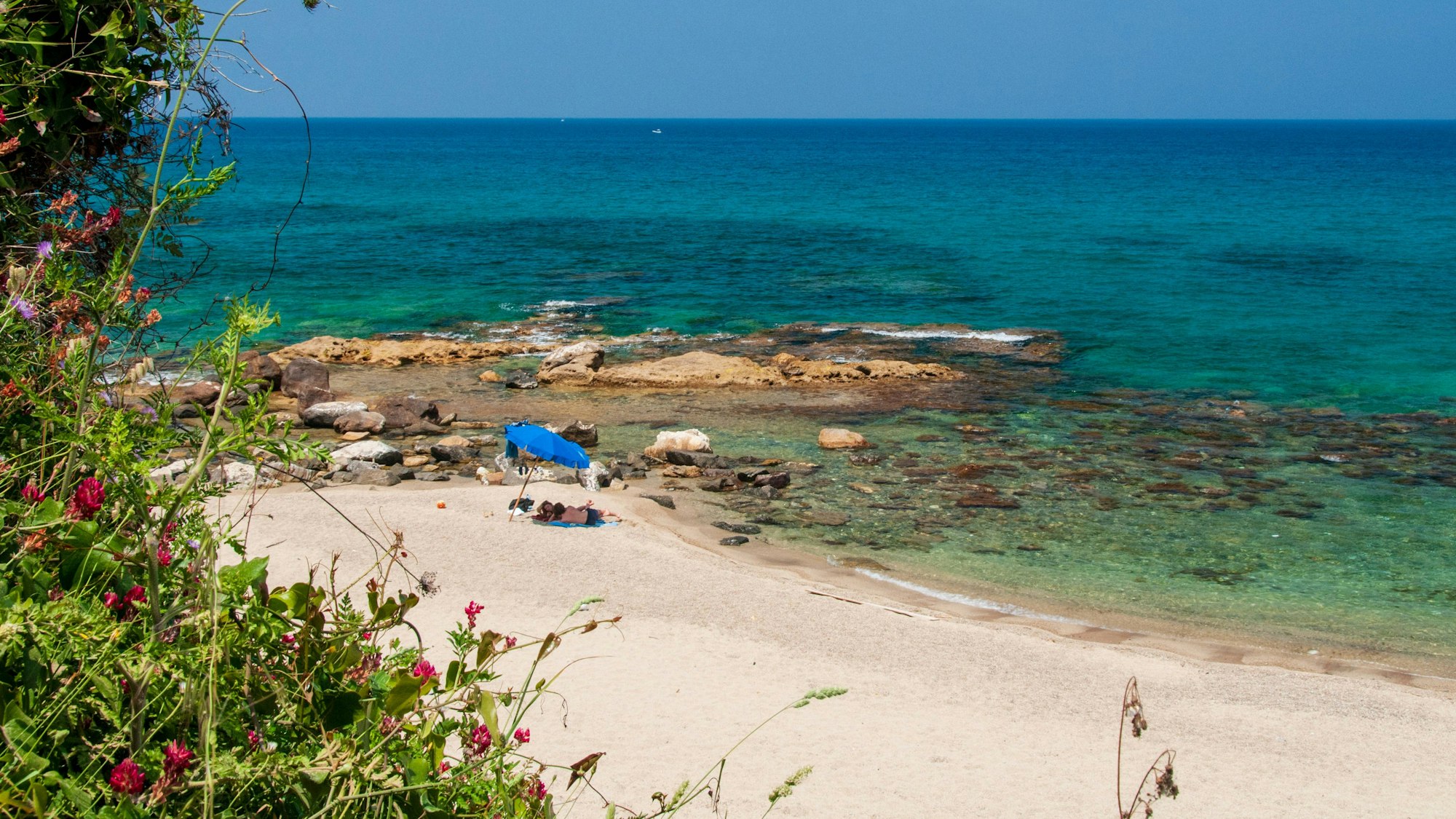 Ein Paar liegt auf Sizilien am Strand.