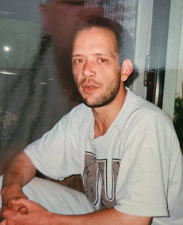 Ein Mann sitzt auf einer Couch und schaut in die Kamera