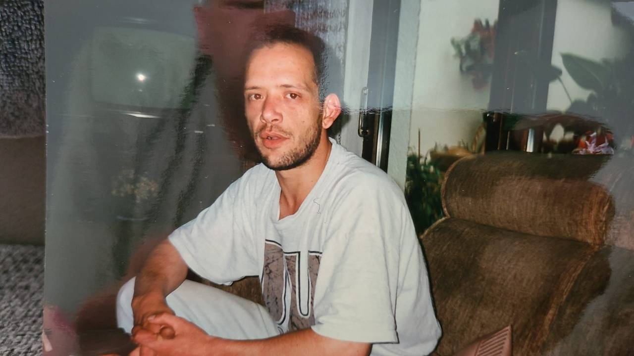 Ein Mann sitzt auf einer Couch und schaut in die Kamera