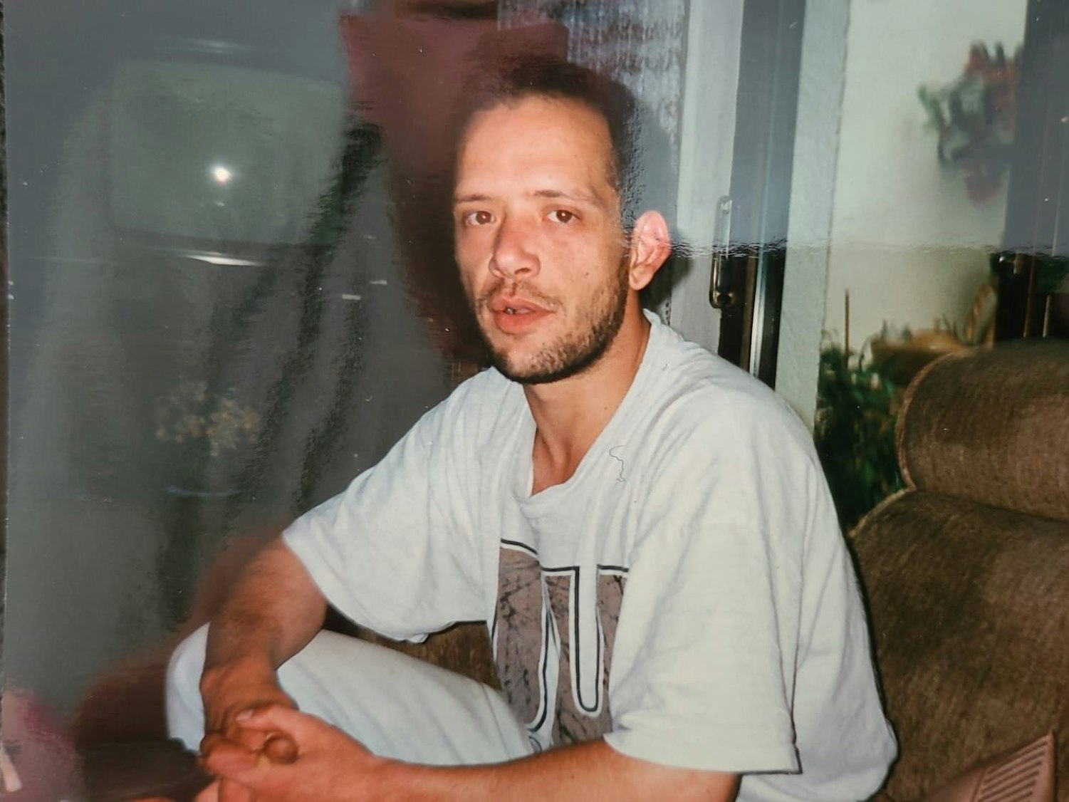 Ein Mann sitzt auf einer Couch und schaut in die Kamera