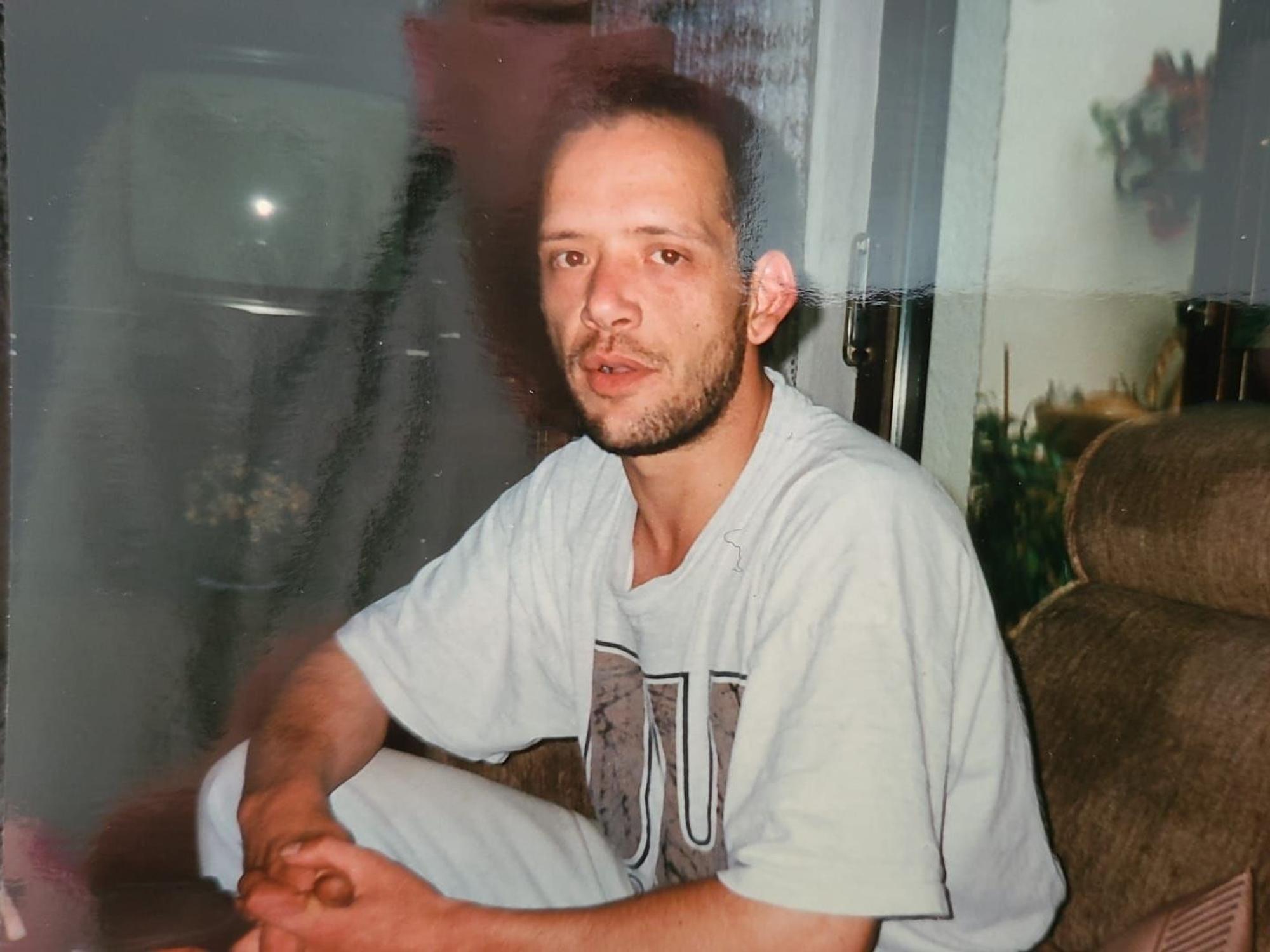 Ein Mann sitzt auf einer Couch und schaut in die Kamera