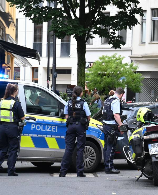 Einsatzkräfte der Polizei stehen mit Streifenwagen und Motorrädern an einer Straßenecke.
