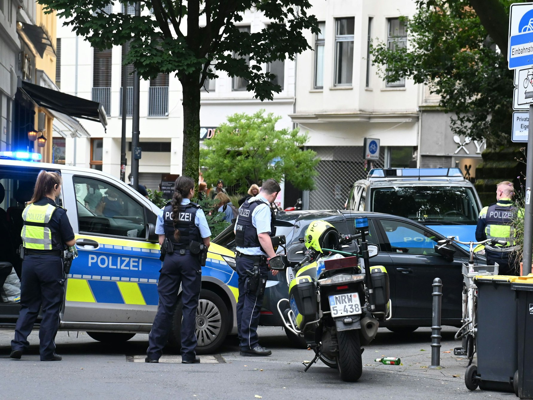 Einsatzkräfte der Polizei stehen mit Streifenwagen und Motorrädern an einer Straßenecke.