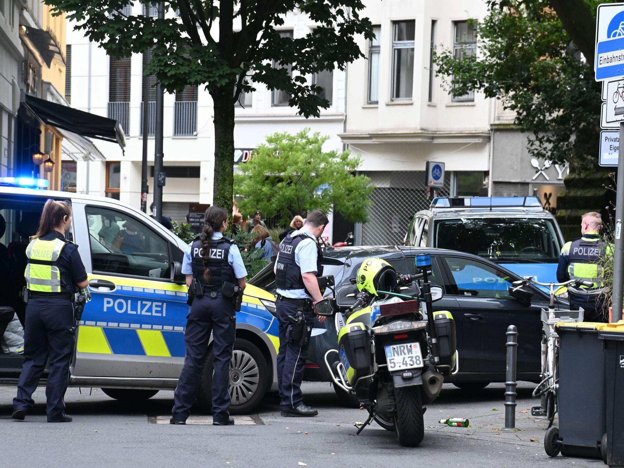 Einsatzkräfte der Polizei stehen mit Streifenwagen und Motorrädern an einer Straßenecke.
