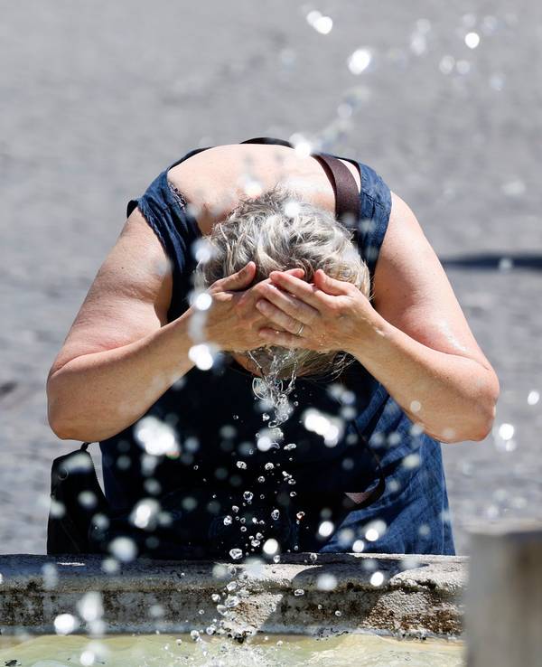Eine Frau kühlt sich am 11. Juli an einem Springbrunnen im Zentrum Roms ab.