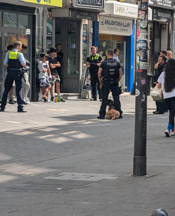Einsatzkräfte der Polizei stehen um mehreren Verdächtige herum.