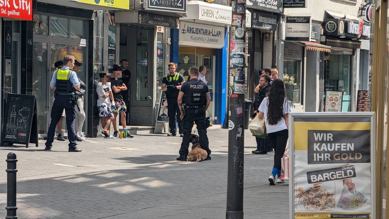 Einsatzkräfte der Polizei stehen um mehreren Verdächtige herum.