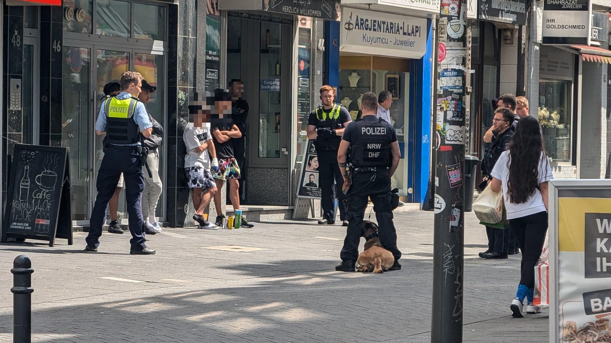 Einsatzkräfte der Polizei stehen um mehreren Verdächtige herum.