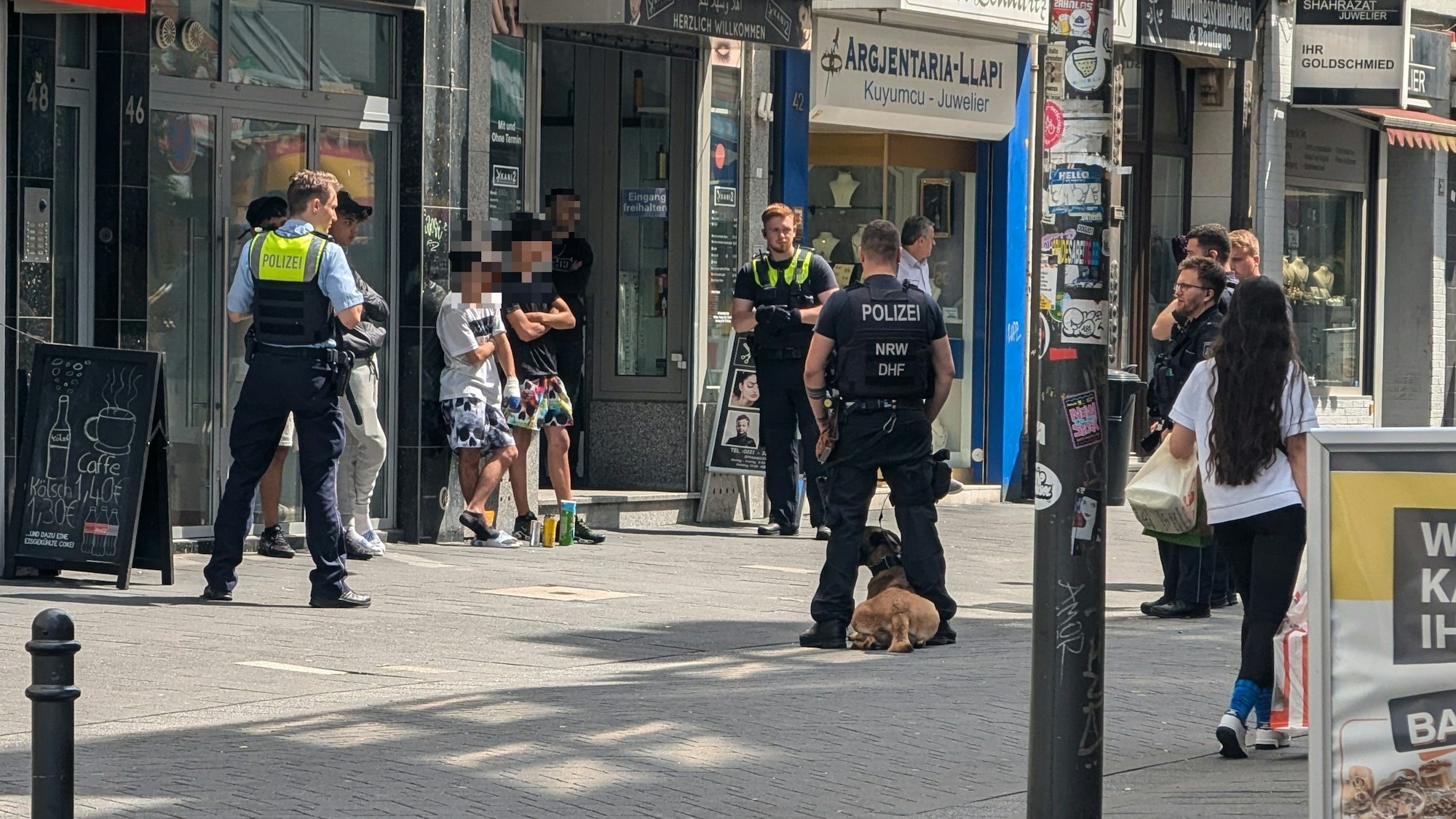 Einsatzkräfte der Polizei stehen um mehreren Verdächtige herum.