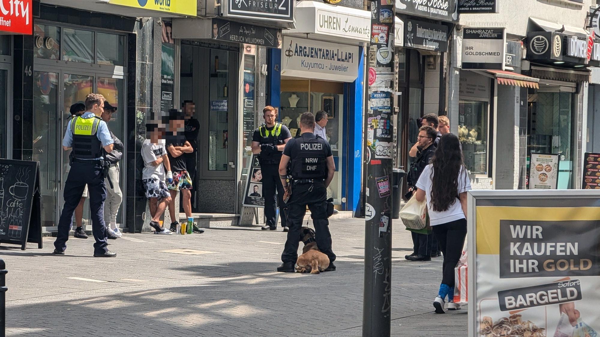 Einsatzkräfte der Polizei stehen um mehreren Verdächtige herum.
