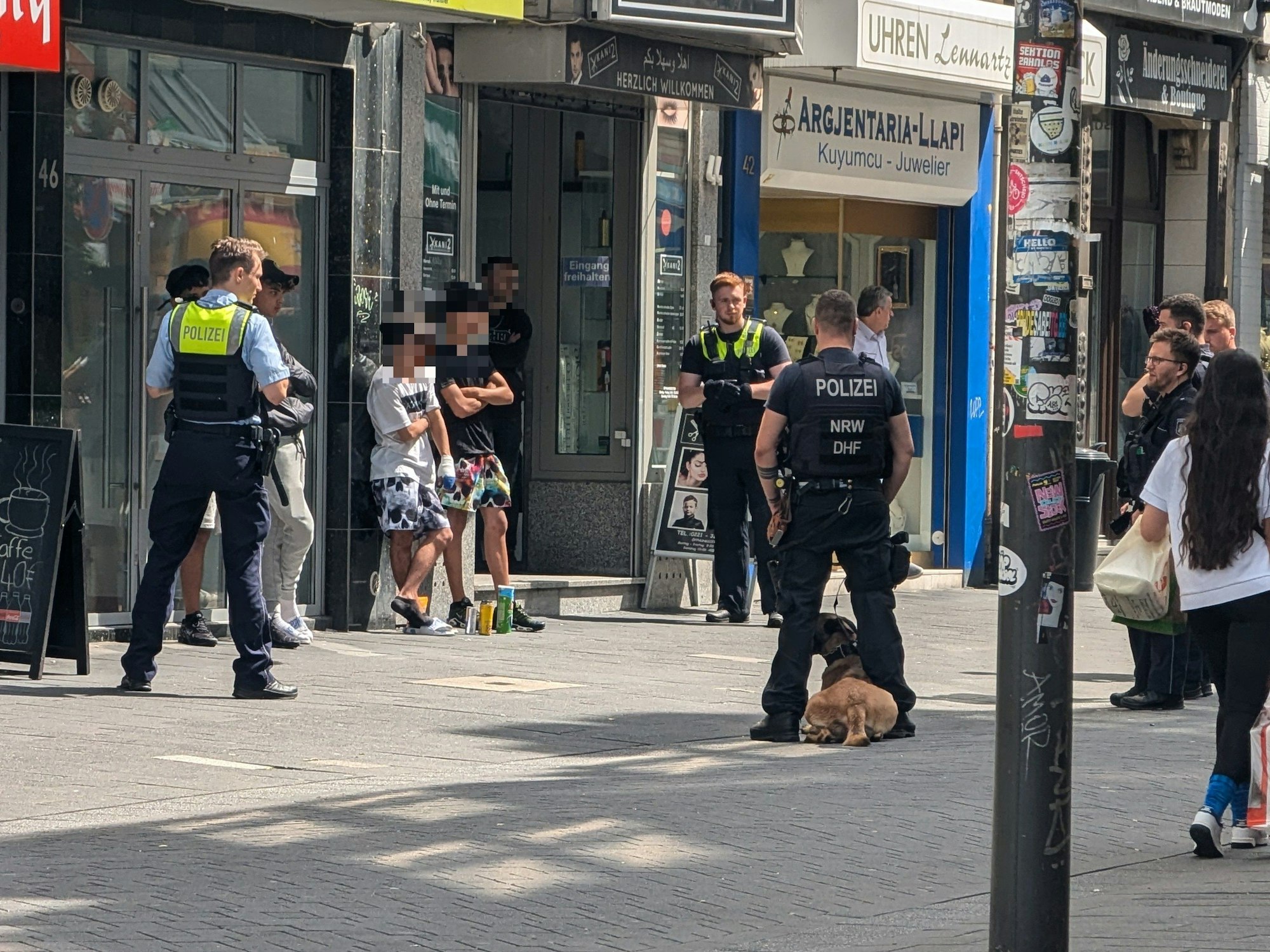 Einsatzkräfte der Polizei stehen um mehreren Verdächtige herum.