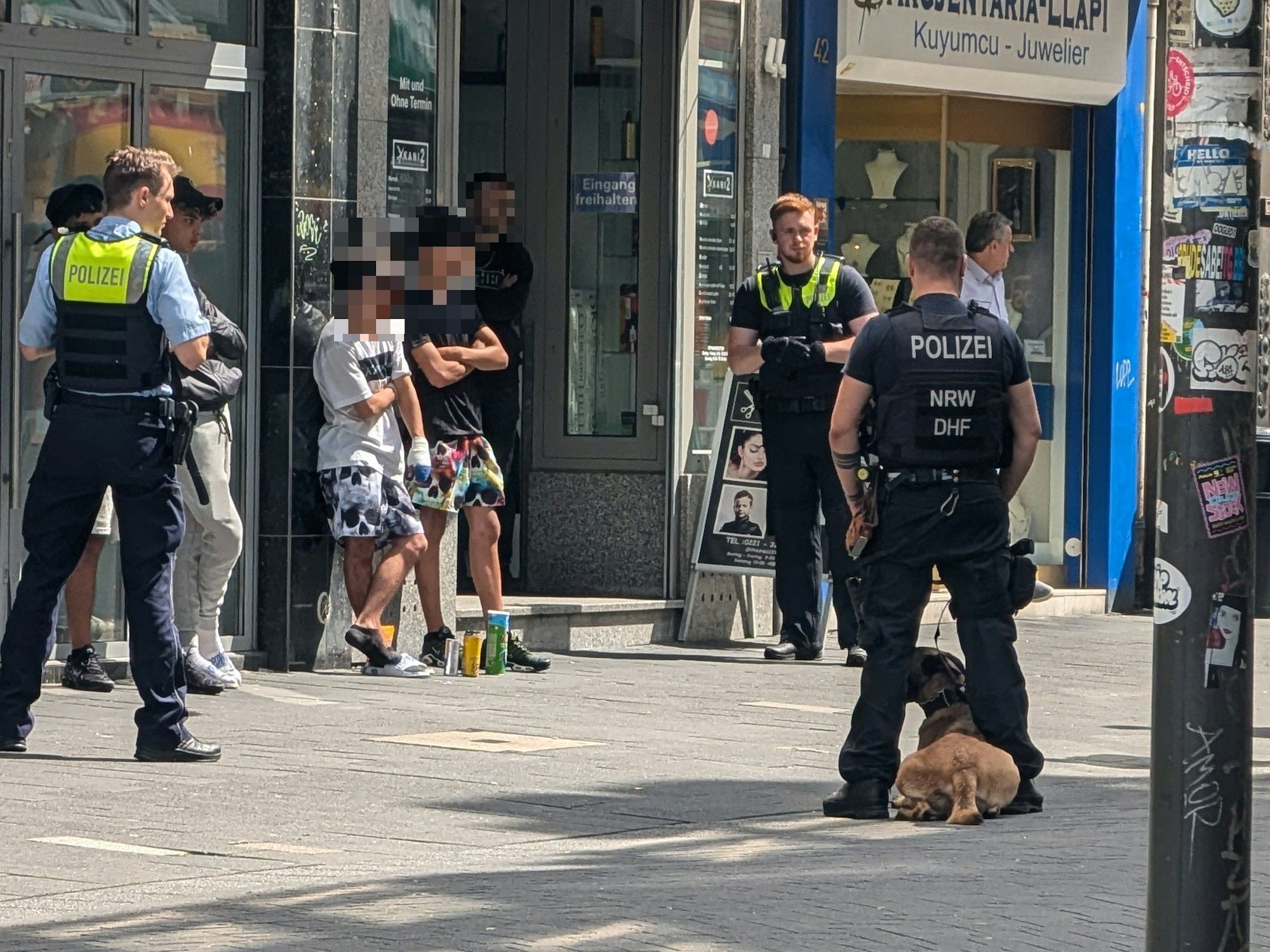 Einsatzkräfte der Polizei stehen um mehreren Verdächtige herum.