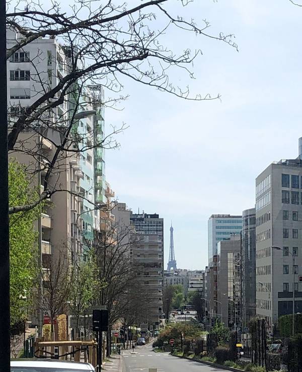 Vor Wohngebäuden am Stadtrand blickt man auf den Eiffelturm.