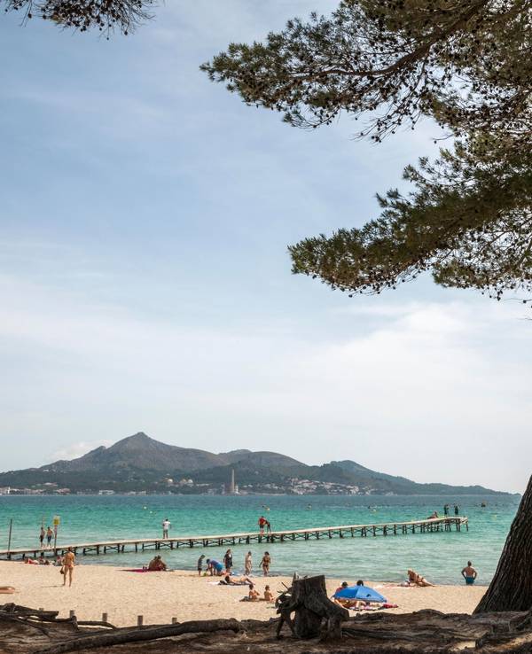 Menschen genießen das schöne Wetter am Strand von Muro auf Mallorca.