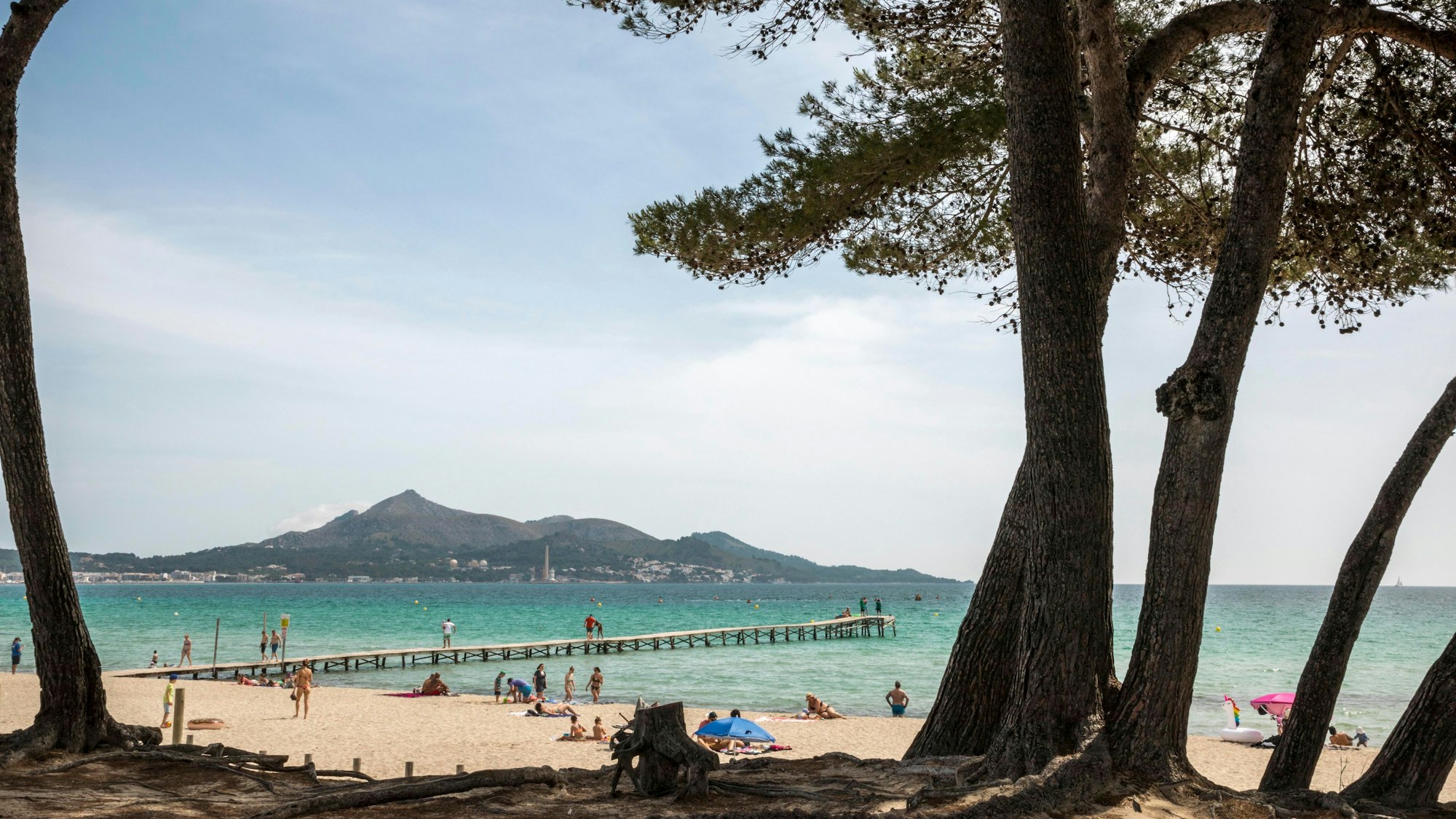 Menschen genießen das schöne Wetter am Strand von Muro auf Mallorca.