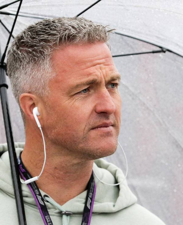 Ralf Schumacher steht bei einer TV-Übertragung zur Formel 1 unter einem Regenschirm.
