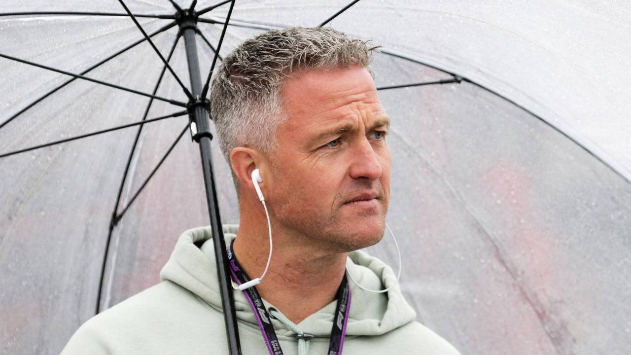 Ralf Schumacher steht bei einer TV-Übertragung zur Formel 1 unter einem Regenschirm.