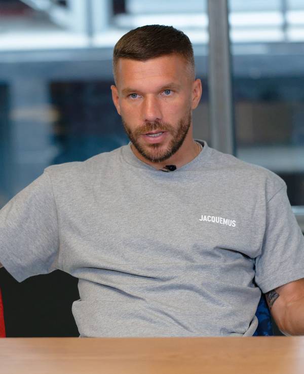 Der Fußballprofi Lukas Podolski sitzt bei einem Interview in einem Besprechungsraum.