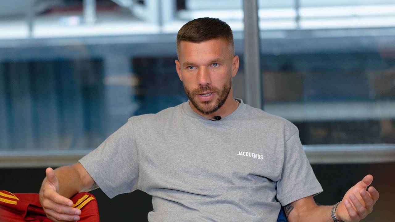 Der Fußballprofi Lukas Podolski sitzt bei einem Interview in einem Besprechungsraum.