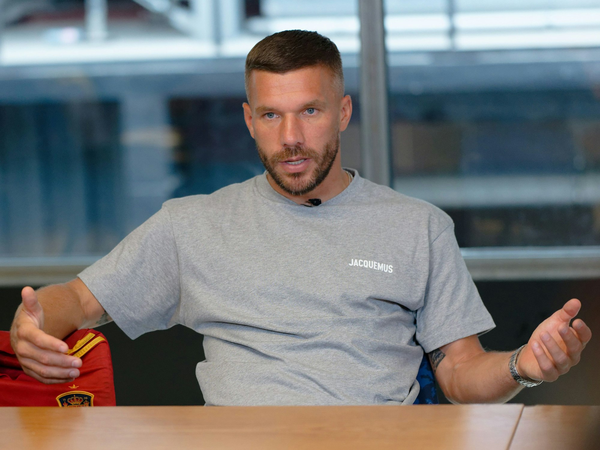 Der Fußballprofi Lukas Podolski sitzt bei einem Interview in einem Besprechungsraum.