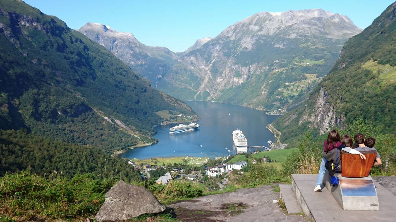 Personenen schauen runter in den Geirangerfjord im Südwesten Norwegens auf die dort liegenden Kreuzfahrtschiffe.