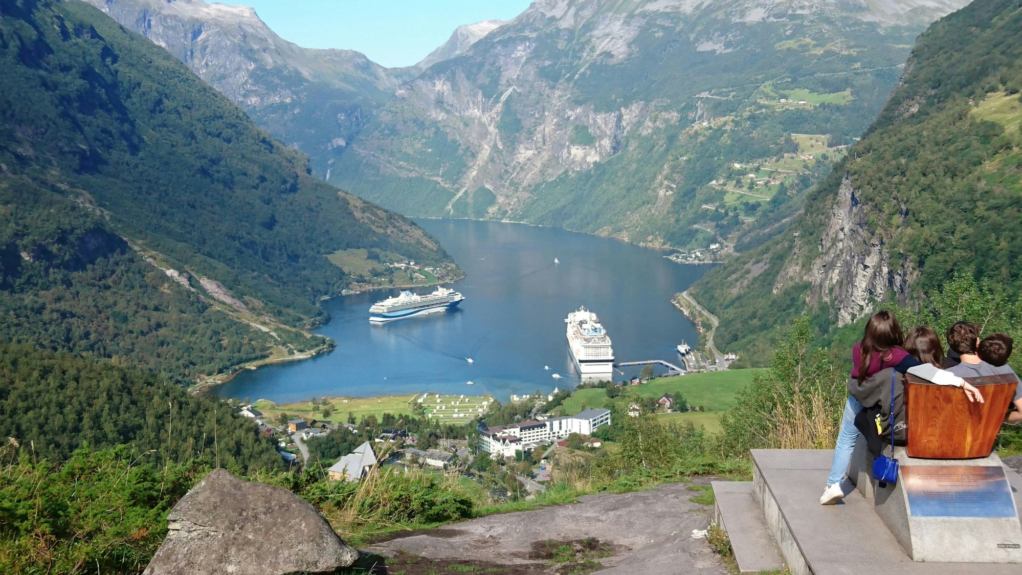 Personenen schauen runter in den Geirangerfjord im Südwesten Norwegens auf die dort liegenden Kreuzfahrtschiffe.