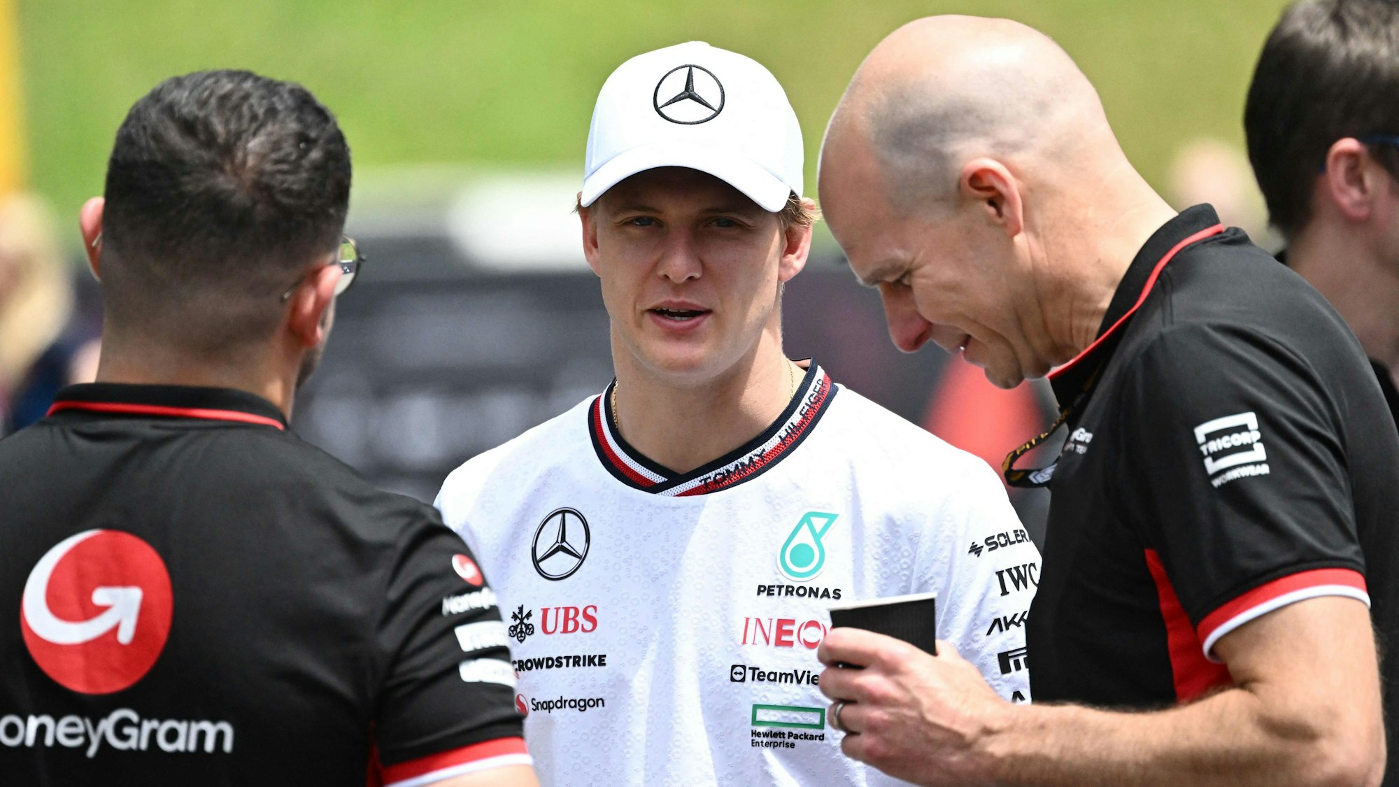 Mick Schumacher unterhält sich mit zwei Haas-Mitarbeitern.