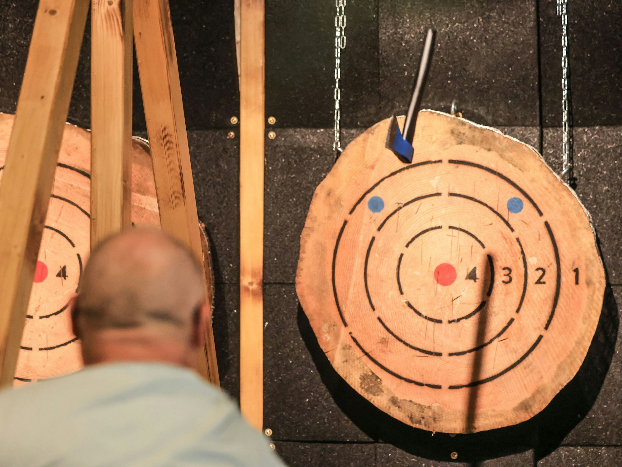 Ein Mann wirft in der Axtwurf-Bar eine Axt auf eine Holzscheibe.