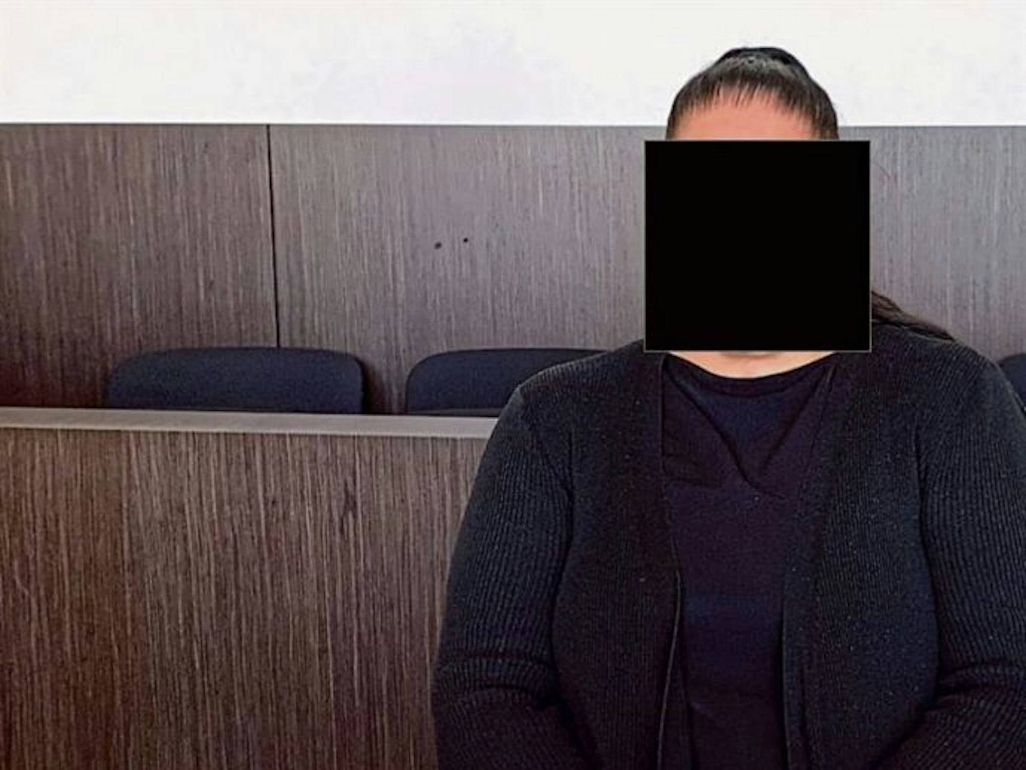 Eine Frau sitzt im Gericht auf der Anklagebank.